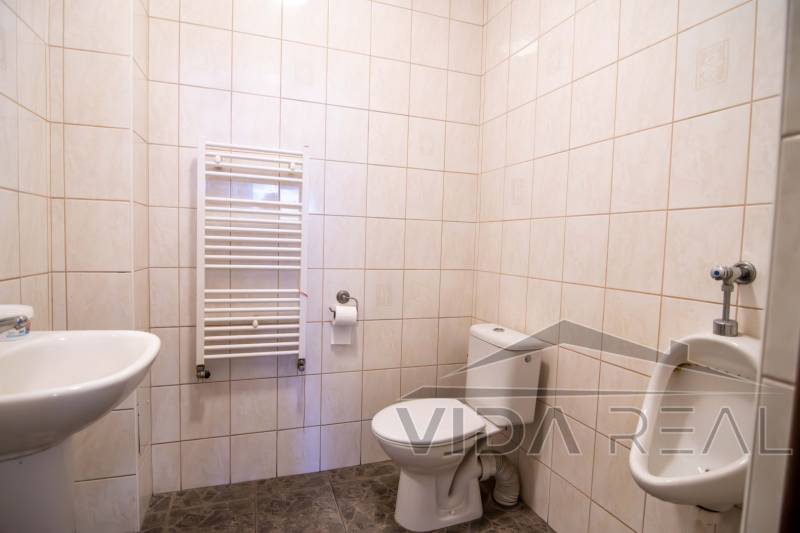 Fürdőszoba raktárakban és csarnokokban WC-vel, piszoárral és a falon radiátorral.