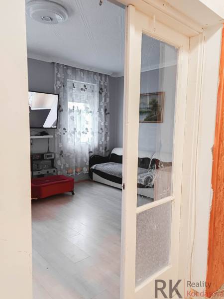 Nappali egy családi házban, televízióval és fa dekorációjú padlóval.