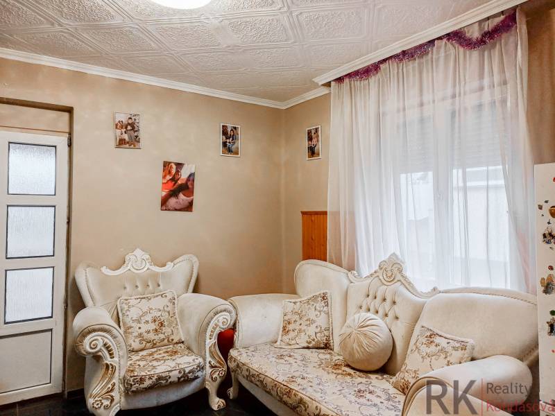 Családi ház nappalija díszes bútorokkal és fényképekkel a falakon.