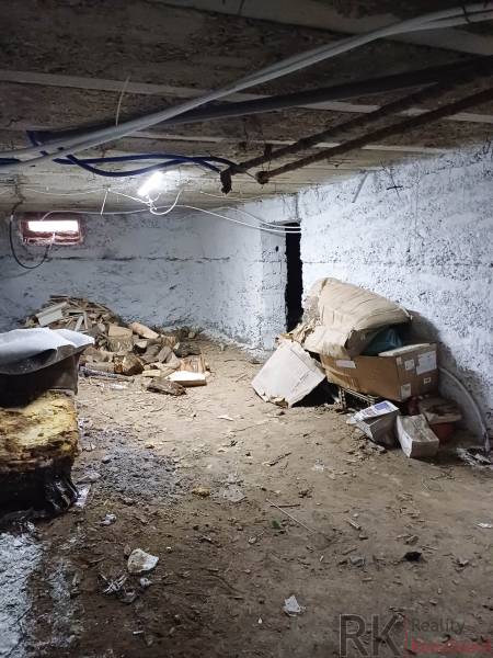 Családi ház alagsora földpadlóval, néhány dobozzal és fával.