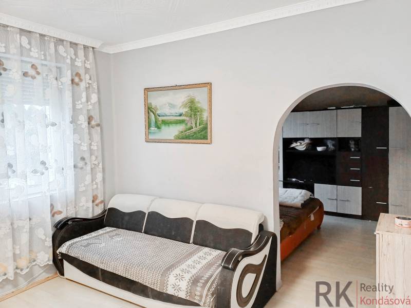 Világos nappali kanapéval, nagy íves átjáróval és virágmintás függönyökkel.