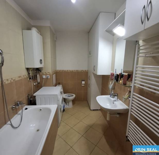 Fürdőszoba egy kétszobás lakásban káddal, mosógéppel és melegvíz-tárolóval.