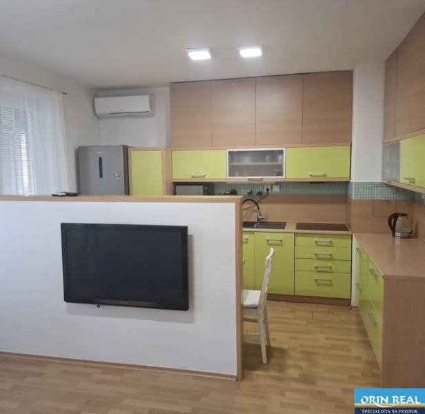 Konyha egy kétszobás lakásban fa dekor padlóval és zöld szekrényekkel.