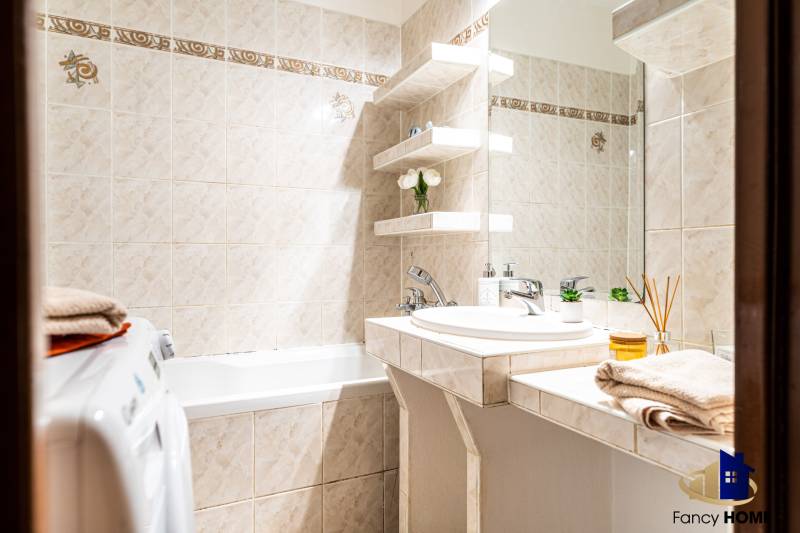 Fürdőszoba háromszobás lakásban, zuhanyzóval, mosdóval és mosógéppel.