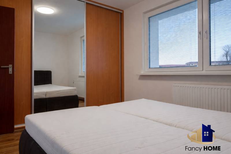 Hálószoba egy háromszobás lakásban nagy ablakkal, beépített szekrénnyel és ággyal.