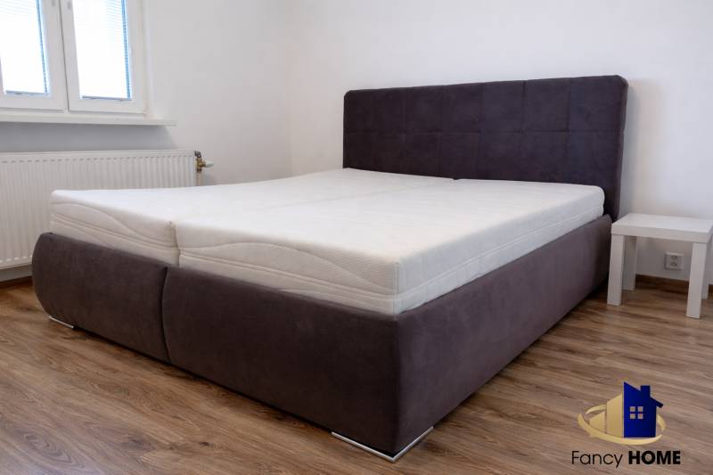 Hálószoba ággyal és fa dekorációjú padlóval egy háromszobás lakásban.