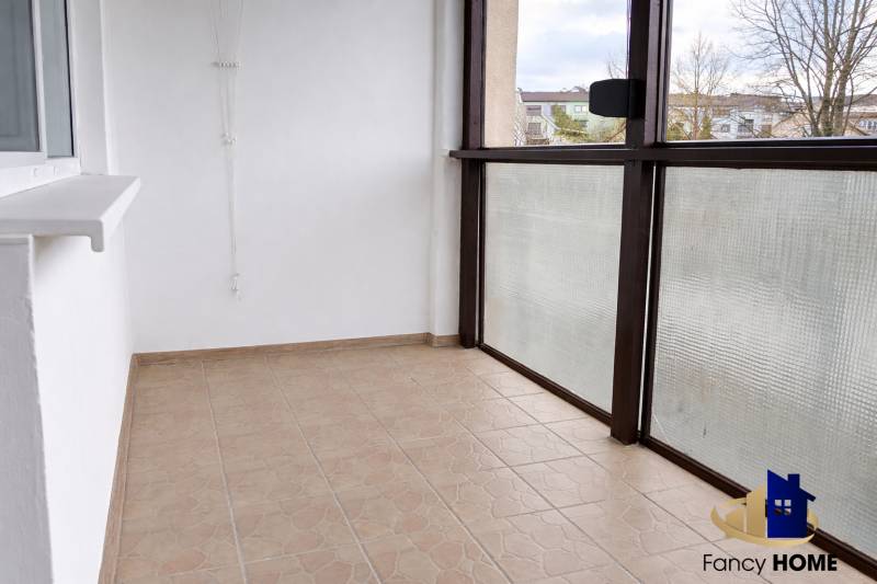 Üvegezett erkély egy 3 szobás lakásban, csempézett padlóval, kilátással a környékre.