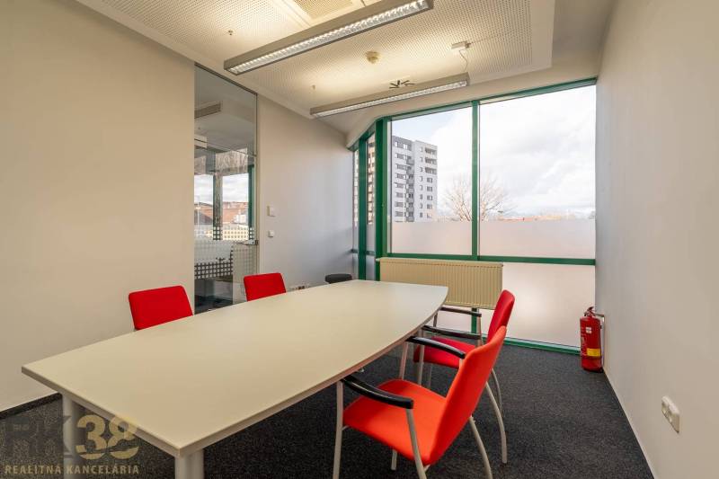 Irodák üvegfallal, fehér asztallal és piros székekkel.