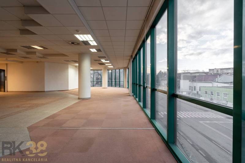 Tágas irodák nagy ablakokkal és széles oszlopokkal, kilátással az utcára.