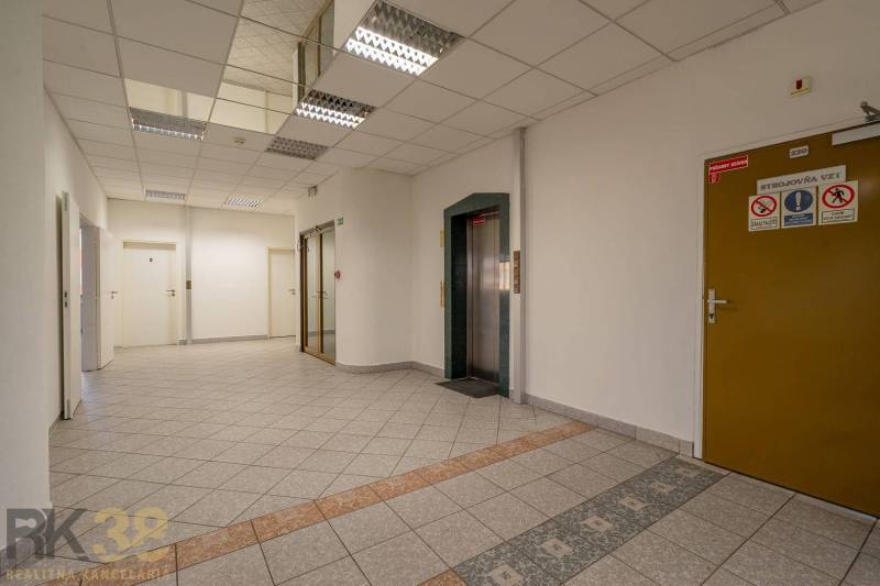 Irodák lifttel és csempével, semleges színek és modern világítás.