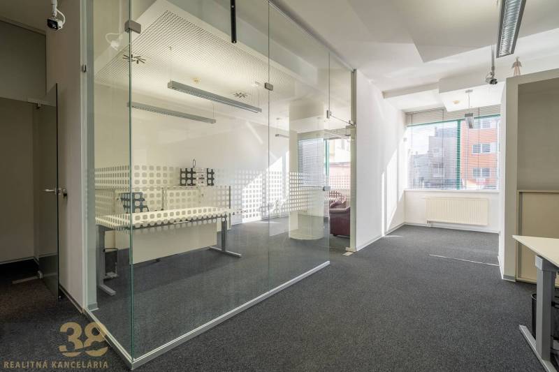 Irodák üveg válaszfalakkal és szőnyegpadlóval, világos terek és természetes fény.