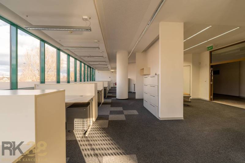 Világos irodák nagy ablakokkal és irodai bútorokkal, fa dekorációjú padlóval.