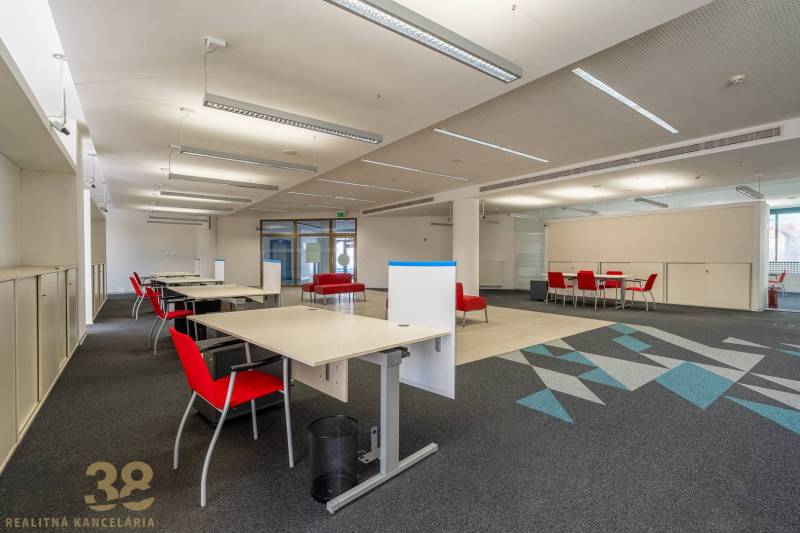 Irodák belső tere piros székekkel és szőnyegmintás padlóval.