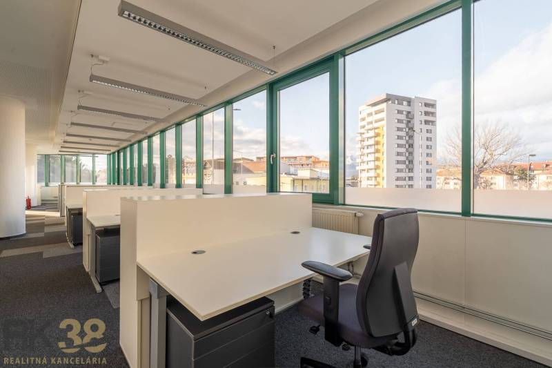 Tágas irodák nyitott boxokkal és nagy ablakokkal, amelyek kilátást nyújtanak a városra.