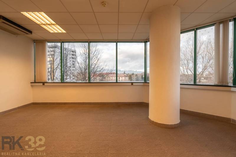 Irodák belső tere nagy ablakokkal és oszloppal, fa dekorációjú padlóval.