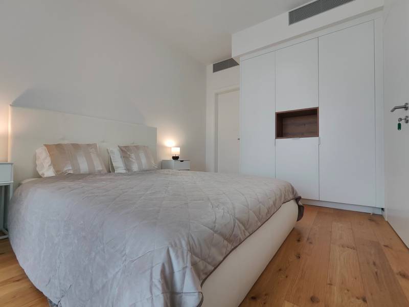 Hálószoba franciaággyal, ruhásszekrénnyel és fa mintázatú padlóval egy kétszobás lakásban.