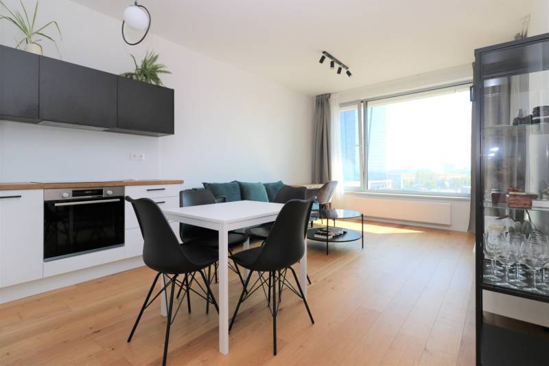 Konyha és étkezőasztal fekete székekkel egy kétszobás lakásban, fa dekorációjú padlóval.