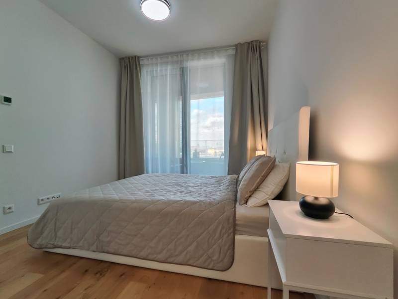 Hálószoba egy kétszobás lakásban ággyal, éjjeliszekrénnyel és fa dekorációjú padlóval.