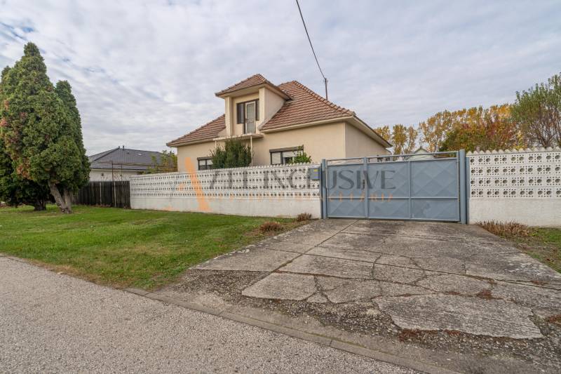 Családi ház Nagydobronyban nagy kerttel, fákkal és beton járdával.