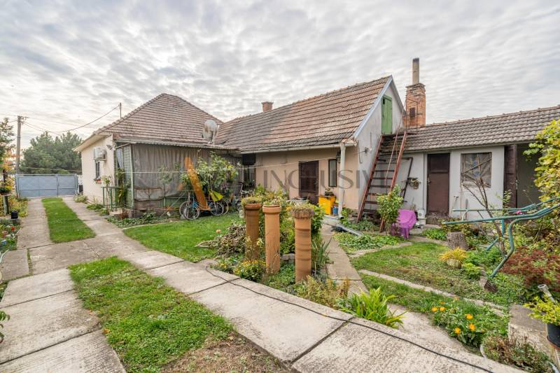 Nagyudvarnokban egy családi ház udvara gyeppel, növényekkel és épületekkel.