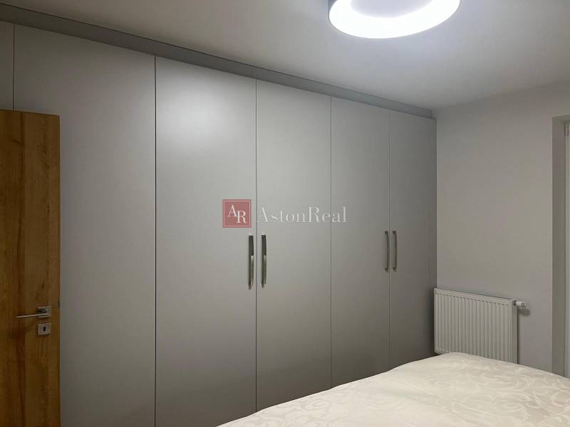 A 3 szobás lakásban fehér tolóajtós szekrények és ágy található.