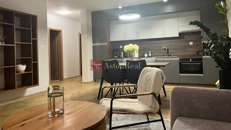 Nappali egy háromszobás lakásban, konyhával, asztallal és fa dekorációjú padlóval.