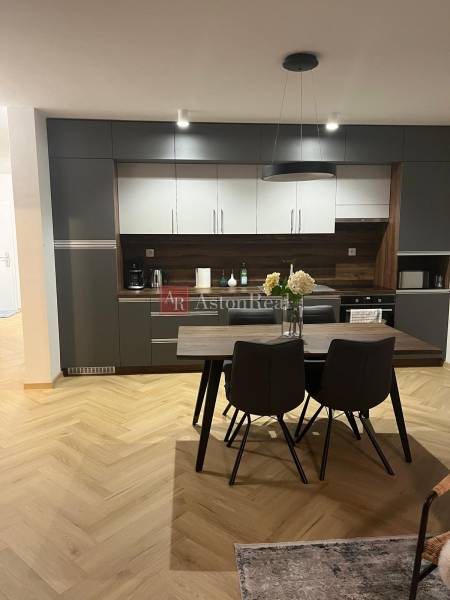 Konyha egy háromszobás lakásban szürke szekrényekkel és fa mintázatú padlóval.