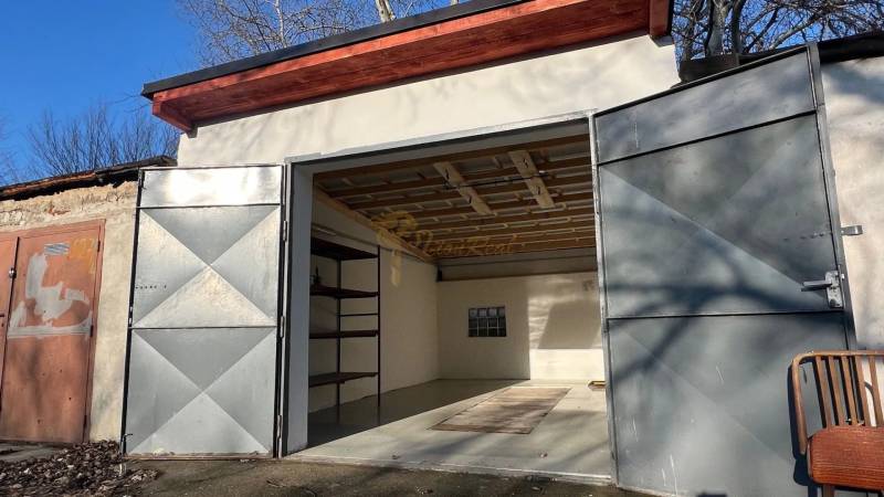 Nyitott garázs az Agátová utcában, Pozsony-Dúbravkán, egyszerű belső térrel és polccal.