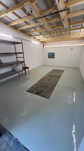 Garázsok polcokkal és világos falakkal, padló járműjavító gödörrel.