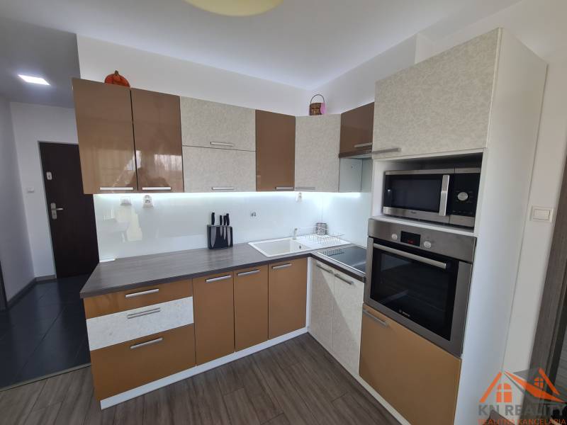 A kétszobás lakás konyhája fa dekor padlóval és modern készülékekkel.