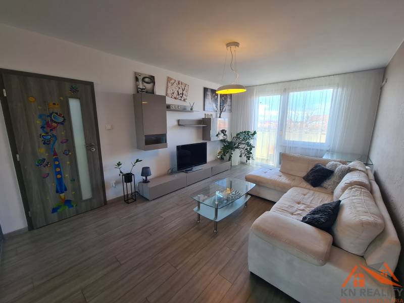 Nappali egy kétszobás lakásban, fa mintázatú padlóval és tágas kanapéval.