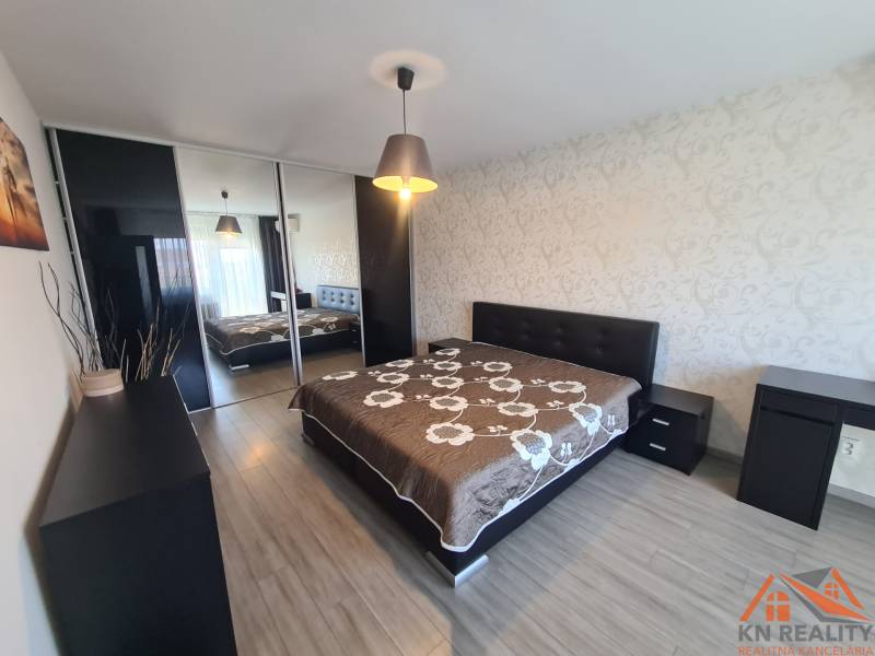 Hálószoba egy kétszobás lakásban nagy ággyal és fa dekorációjú padlóval.