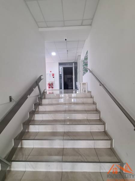 Fehér falú és csempézett padlójú lépcső vezet a kétszobás lakás bejáratához.