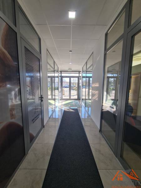 Világos folyosó üvegajtókkal és márványpadlóval Komáromban, alkalmas 2 szobás lakás számára.