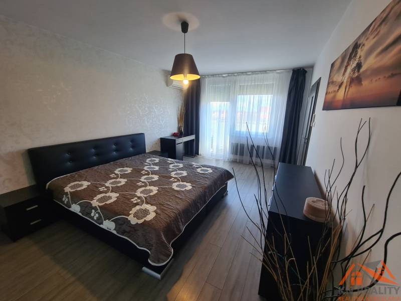 Hálószoba egy kétszobás lakásban ággyal, szekrénnyel és fa dekorációjú padlóval.