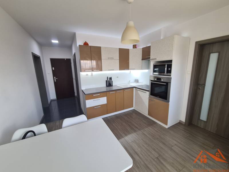 Konyha háztartási gépekkel és asztallal, fa dekor padlóval a kétszobás lakásban.