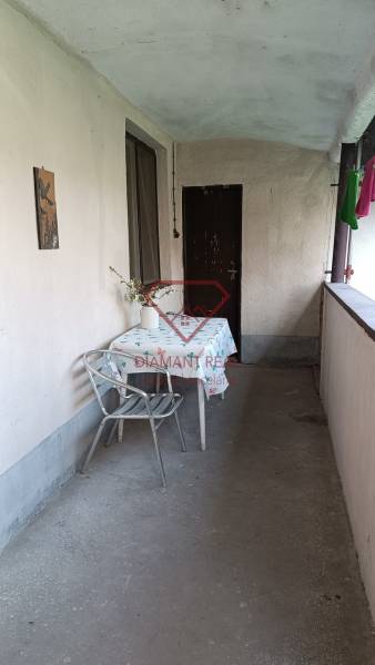 Fedett terasz családi házban, asztal székkel, váza virágokkal, lakótér.