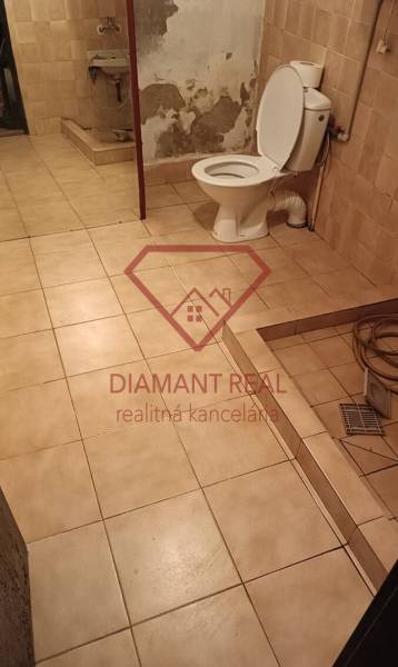 Fürdőszoba családi házban WC-vel, mosdóval és padlócsempével.