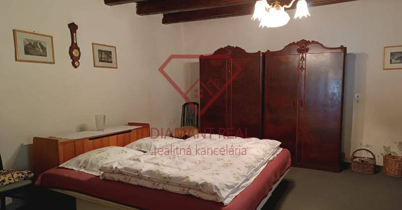 Hálószoba családi házban fa mennyezettel, antik szekrénnyel és klasszikus csillárral.