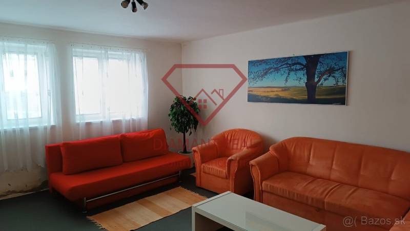 Nappali egy családi házban narancssárga kanapéval, fotelekkel és tájképpel.