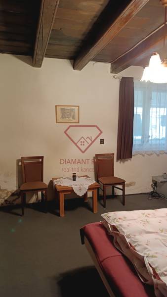 Szoba családi házban fa mennyezettel, két székkel és egy asztallal.