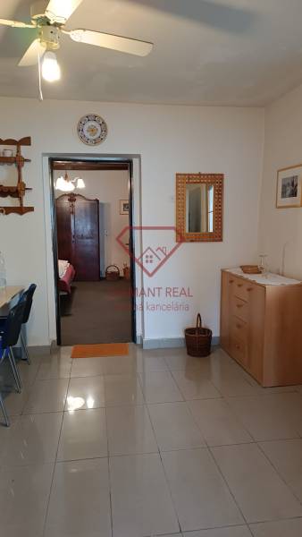Családi ház belső tere járólappal, fa komóddal és mennyezeti ventilátorral.