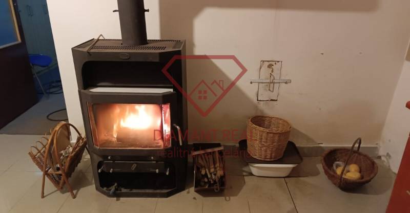 Cserépkályha egy családi házban, mellette kosarak fával és gyümölccsel.