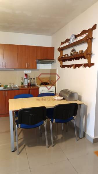 Ebédlő egy családi házban konyhabútorral, asztallal és fali polccal.