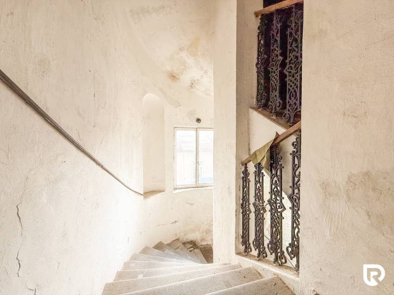 Családi ház lépcsője ablakkal és díszes korláttal, fehér fal patinával.