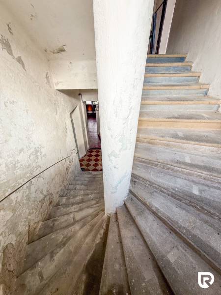 A családi ház belsejébe vezető lépcső, amelynek falain kopott vakolat van.