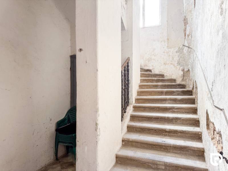 Családi ház lépcsője műanyag székek halmával. Kopott falak.