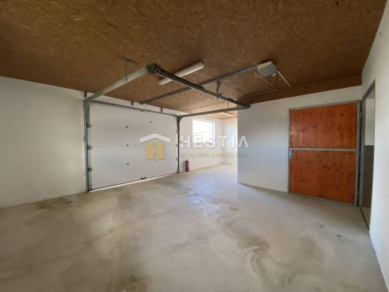 Raktárak és csarnokok betonpadlóval, fa mennyezettel és nagy garázskapukkal.