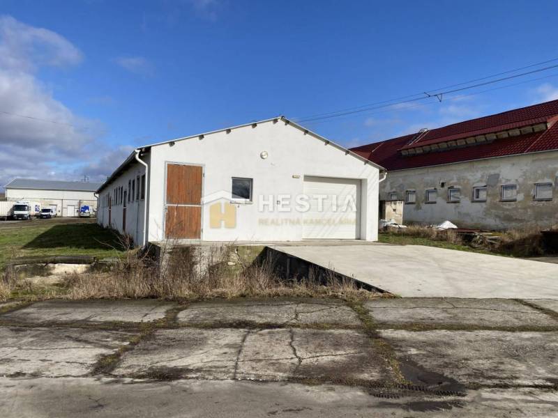 Raktárak és csarnokok külső része Rybkyben fehér homlokzattal és faajtókkal.