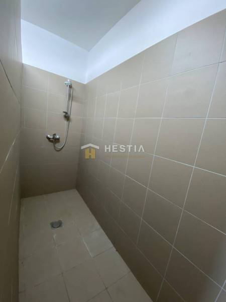 Zuhanyzó bézs csempékkel egy ipari csarnokban.